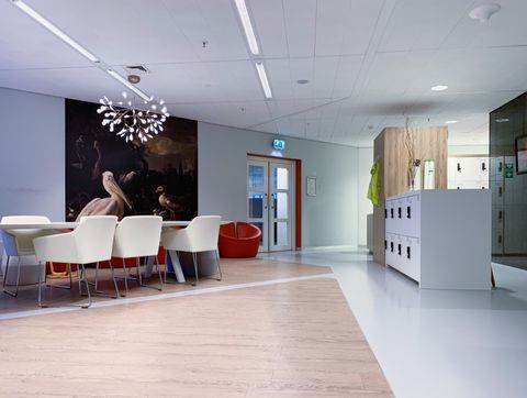 Ontvangstruimte met witte stoelen, een groot schilderij en een designlamp