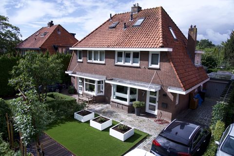 Vrijstaande woning met rode pannendaken en aangelegde tuin, vanuit de lucht gefotografeerd