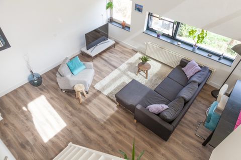 Woonkamer van bovenaf gefotografeerd, met lichte houten vloer en grijze hoekbank