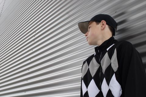 Portret van een jongen met pet voor een golfplaten wand