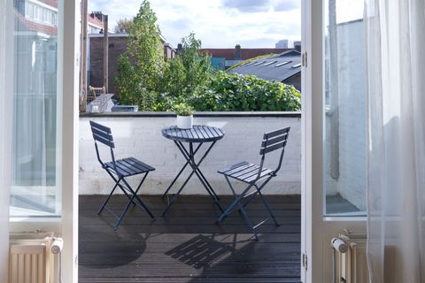 Balkon met bistrotafel en twee stoelen, gezien door openstaande deuren